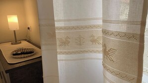 A hotel room with a bedside lamp, a remote control on a mat, and a curtain with a geometric pattern. - Double Room with private bathroom in Terralba (Oristano) - Juniper (Terralba)