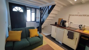 A compact living space with a sofa, a kitchenette, and a staircase.