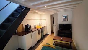 A compact kitchen with a coffee maker, toaster, and sink. A small seating area with a table and cushions is visible.