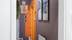 Een gang met een paarse muur, een oranje deur en beelde op de wand.