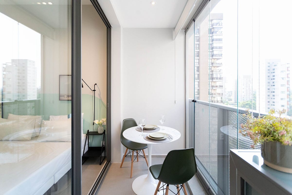 Un balcón moderno con una mesa de comedor, sillas y una planta en maceta.