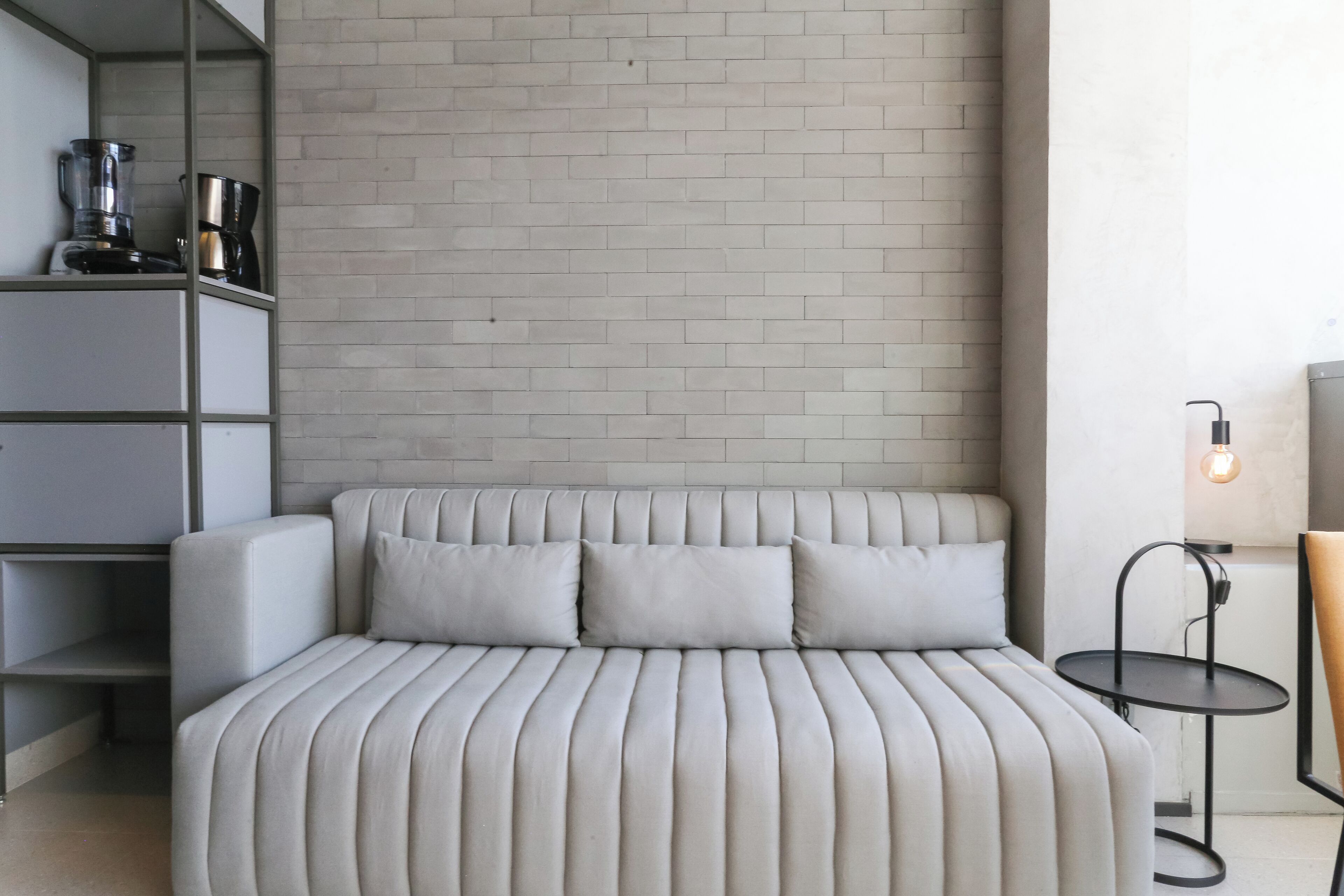 Ein modernes Zimmer mit einer Couch, einer Kaffeemaschine und einem kleinen Tisch mit einer Lampe.