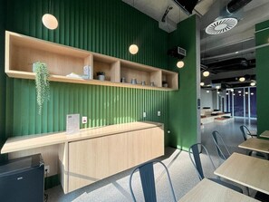 Ein modernes Interieur mit grüner Wand, Holztresen und Metallstühlen.