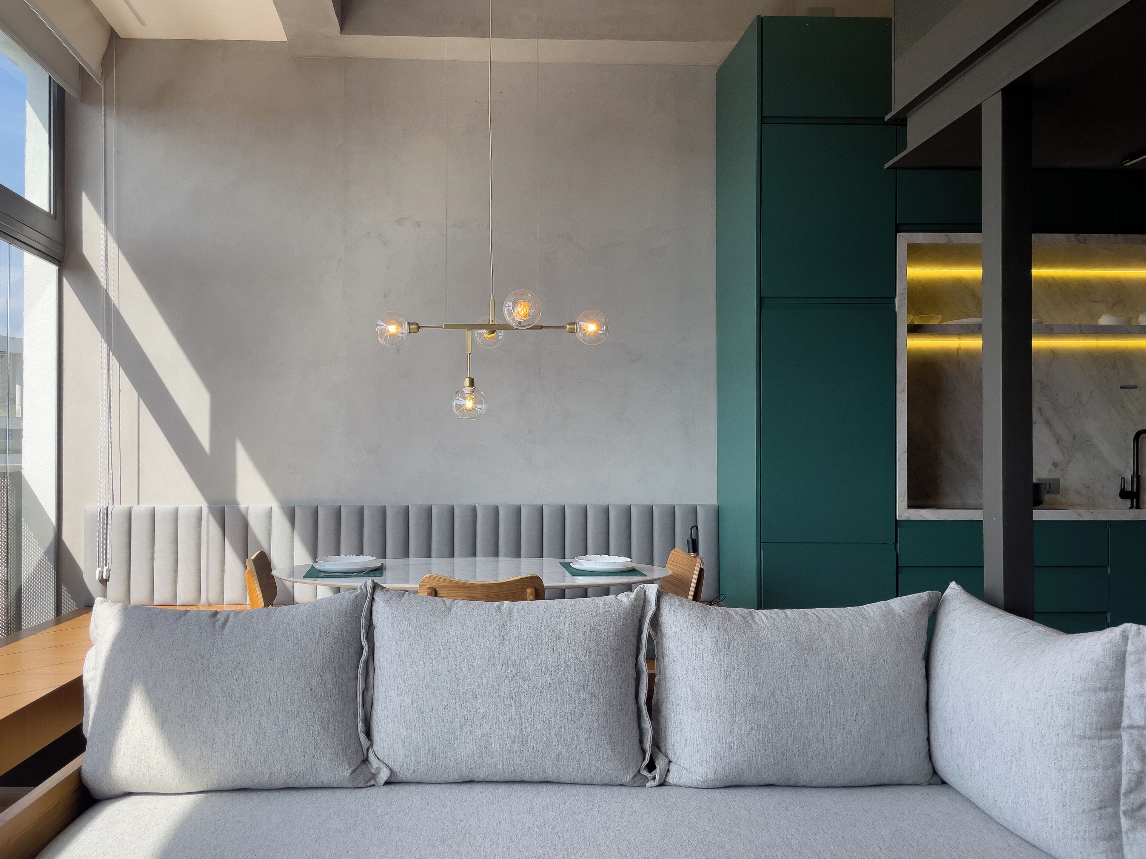 Et moderne spiseområde med bænk og hængende lampe, samt udsigt til køkkenet.