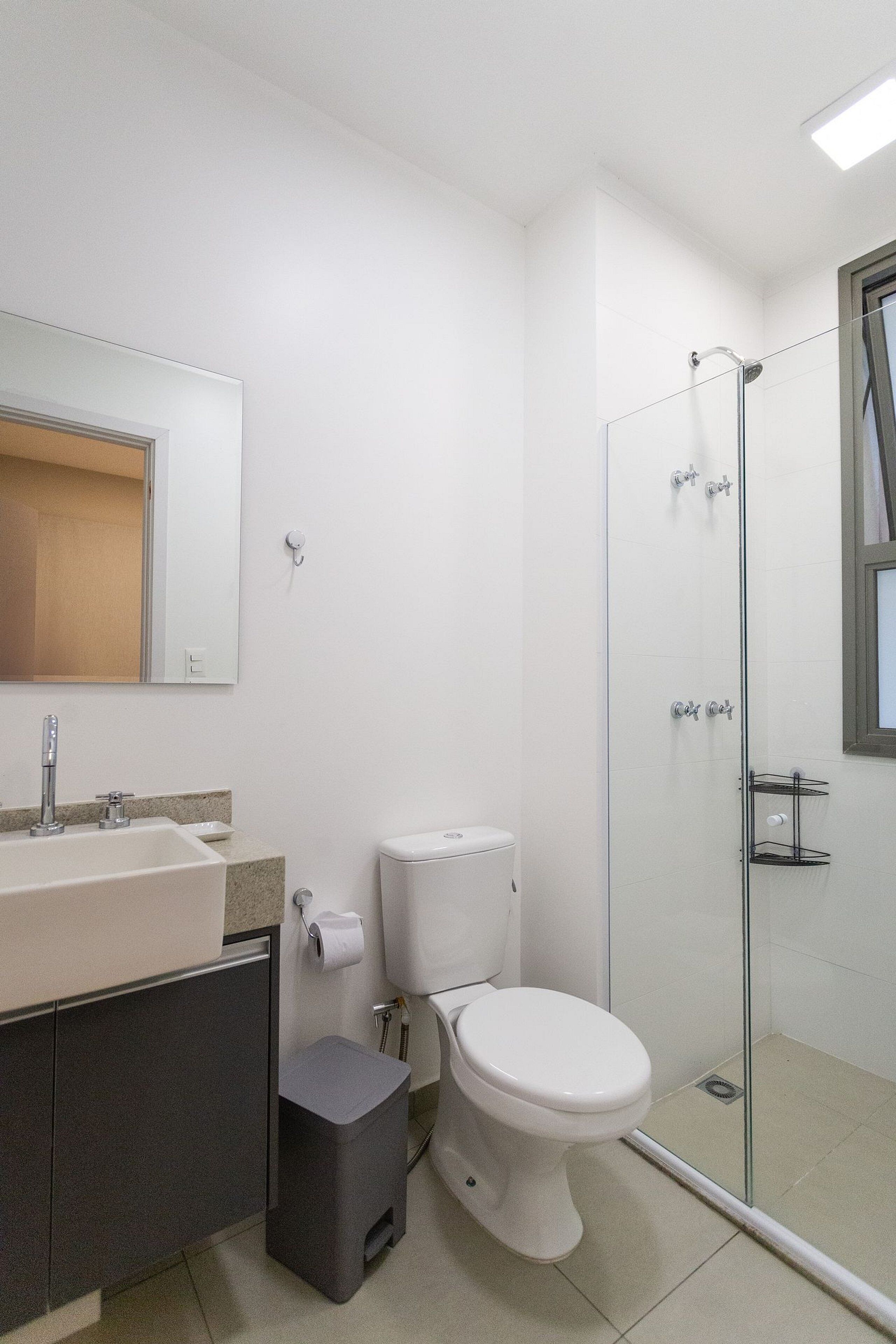 Une salle de bain avec un lavabo blanc, des toilettes et une douche à parois de verre.