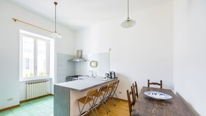Una cocina con una isla central, sillas de madera, una mesa de comedor e iluminación colgante.