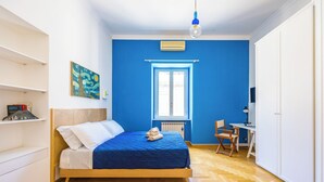 Un dormitorio con cama, escritorio, silla, radiador y ventana.
