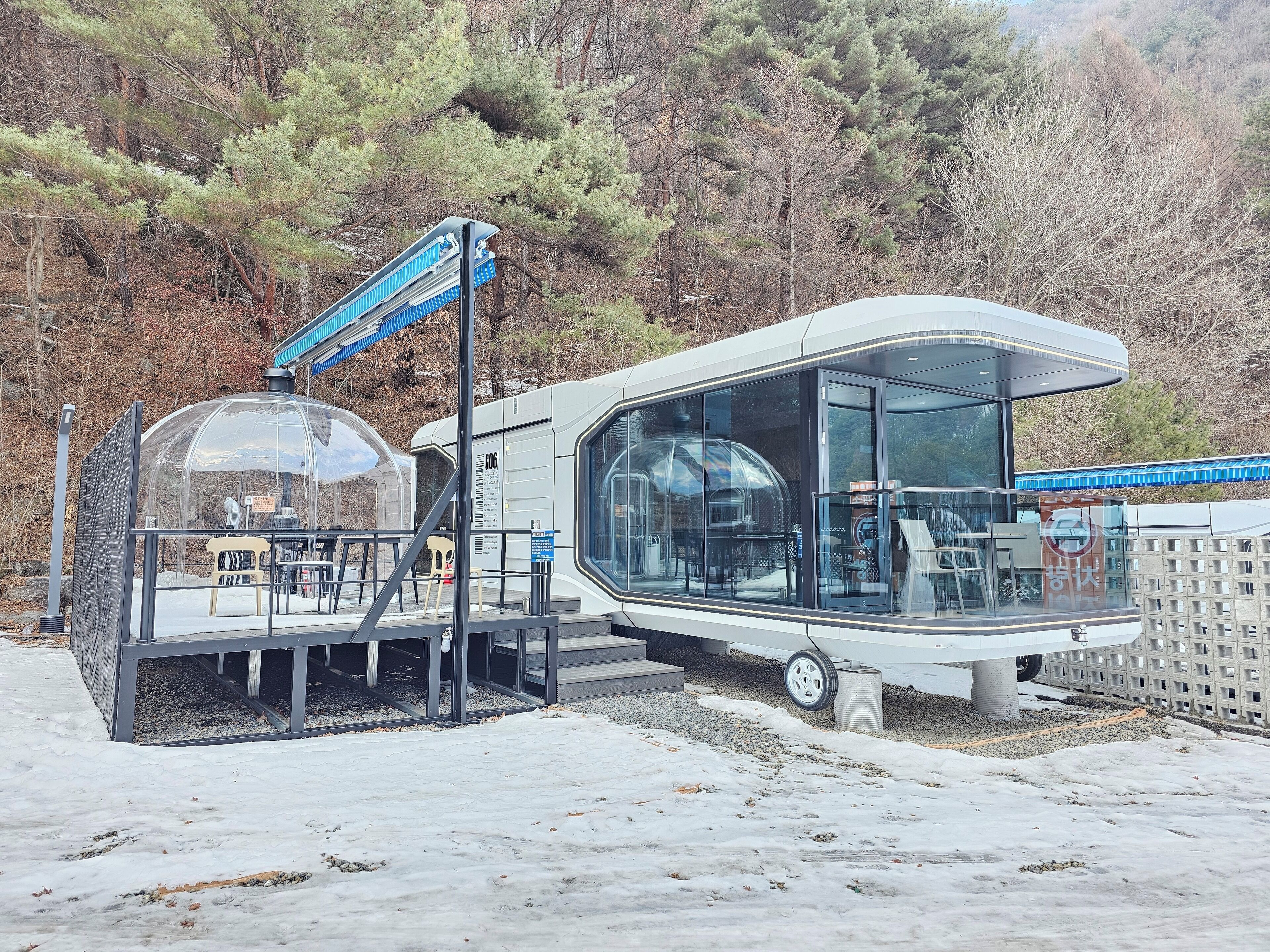 Una autocaravana moderna amb una cúpula transparent i una zona de terrassa coberta.
