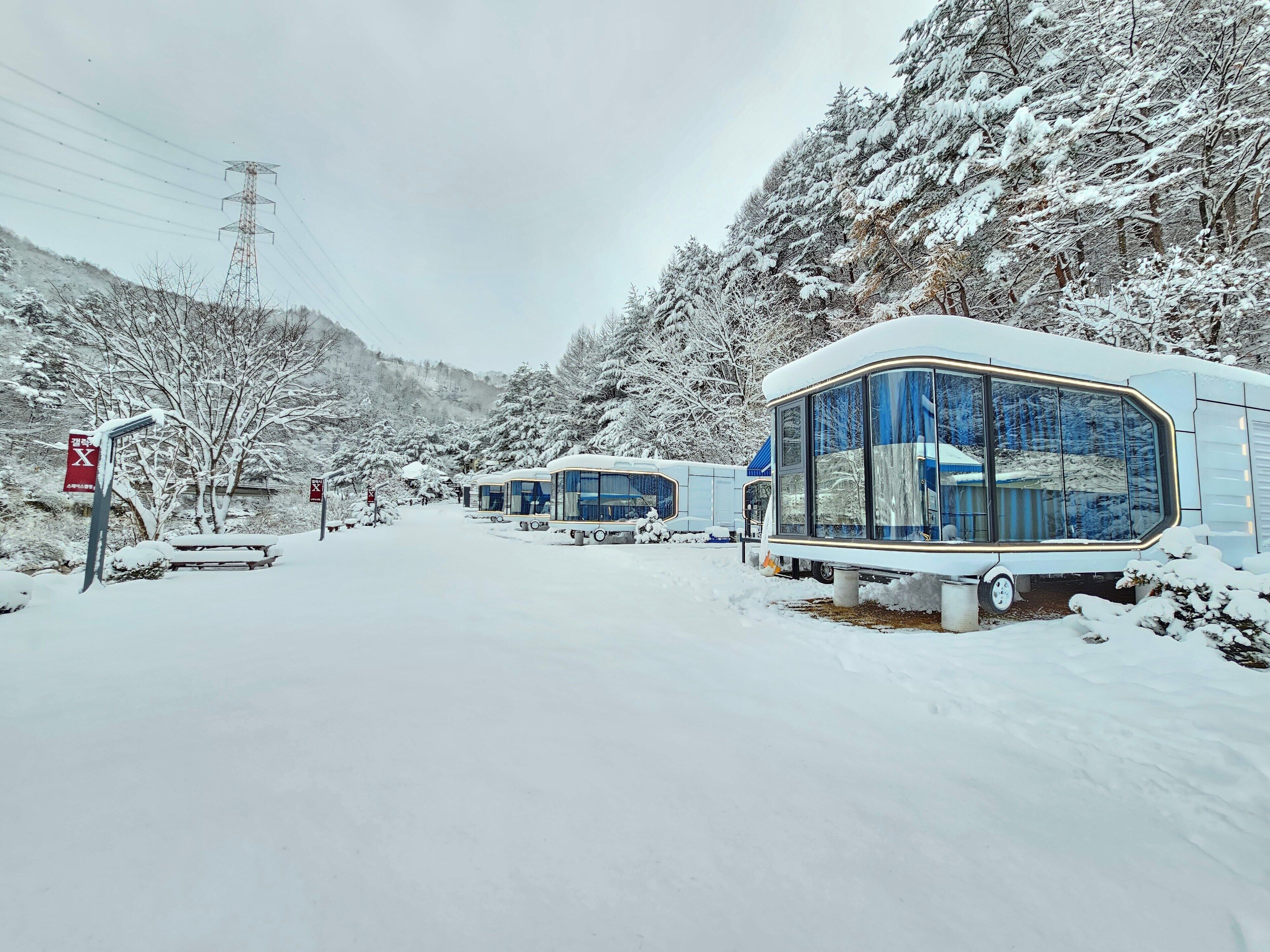 Zona nevada con cabañas modernas de fachada de vidrio.