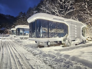 A row of snow-covered RVs parked on a snow-laden road with a forested backdrop. - Galaxy x Hotel type Caravan Glamping&Pension (Pyeongchang)