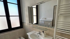 A modern bathroom with a large window, a bidet, a sink with a mirror above, and a towel rack. - Double Room with private bathroom in Terralba (Oristano) – Ginestra (Terralba)