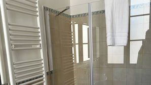 A shower with a glass door, a white towel hanging on the wall, and a white towel rack. - Double Room with private bathroom in Terralba (Oristano) – Ginestra (Terralba)