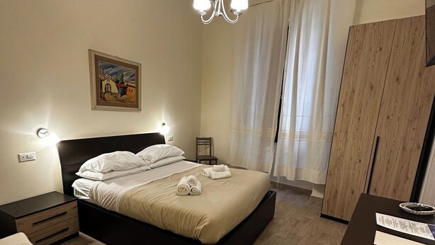 A bedroom with a bed, bedside tables, a desk, a chair, a wardrobe, and a chandelier. - Double Room with private bathroom in Terralba (Oristano) – Ginestra (Terralba)
