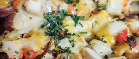 A close-up of a dish with diced potatoes, cheese, and herbs.