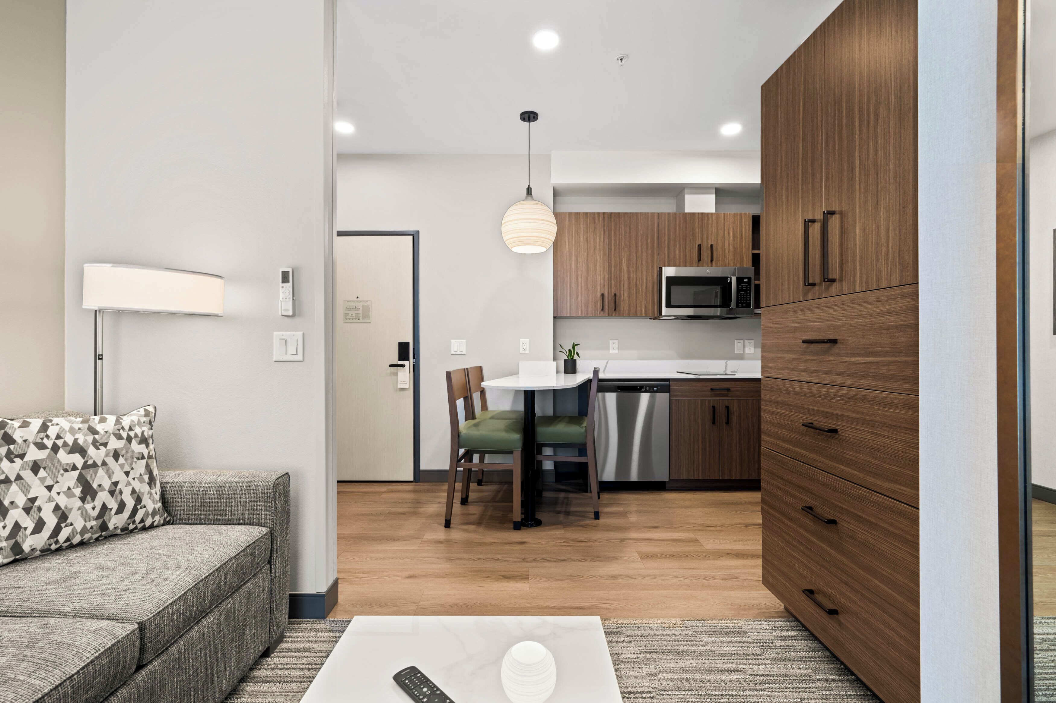 A modern living room with a sofa, a coffee table, and a dining area with a table and chairs.