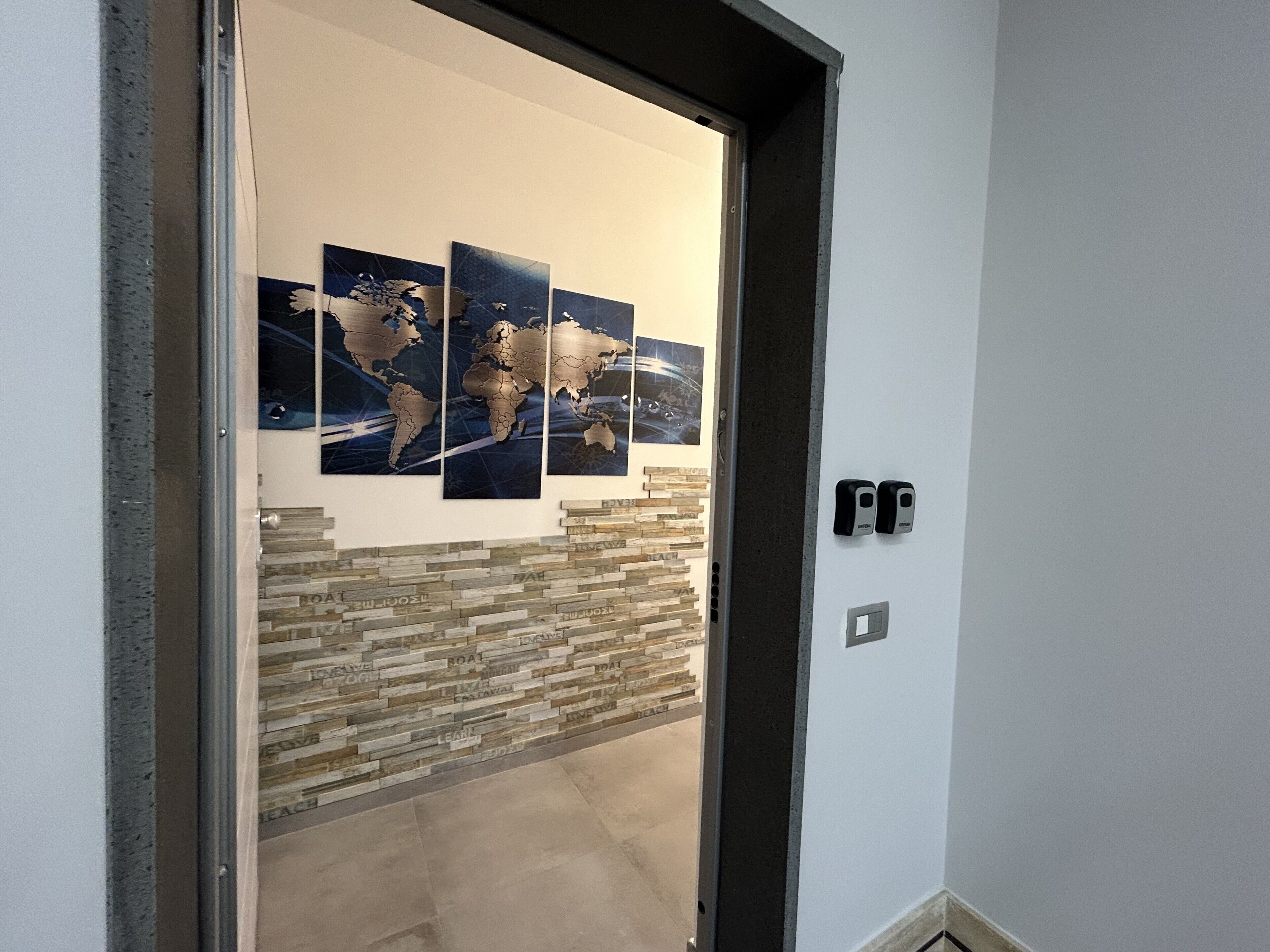 A hallway with a stone wall and three world maps on the wall.
