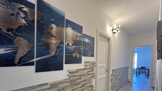 Ein Flur mit Wandgemälde einer Weltkarte, einer Wand mit Holzvertäfelung und einem Essbereich im Hintergrund.