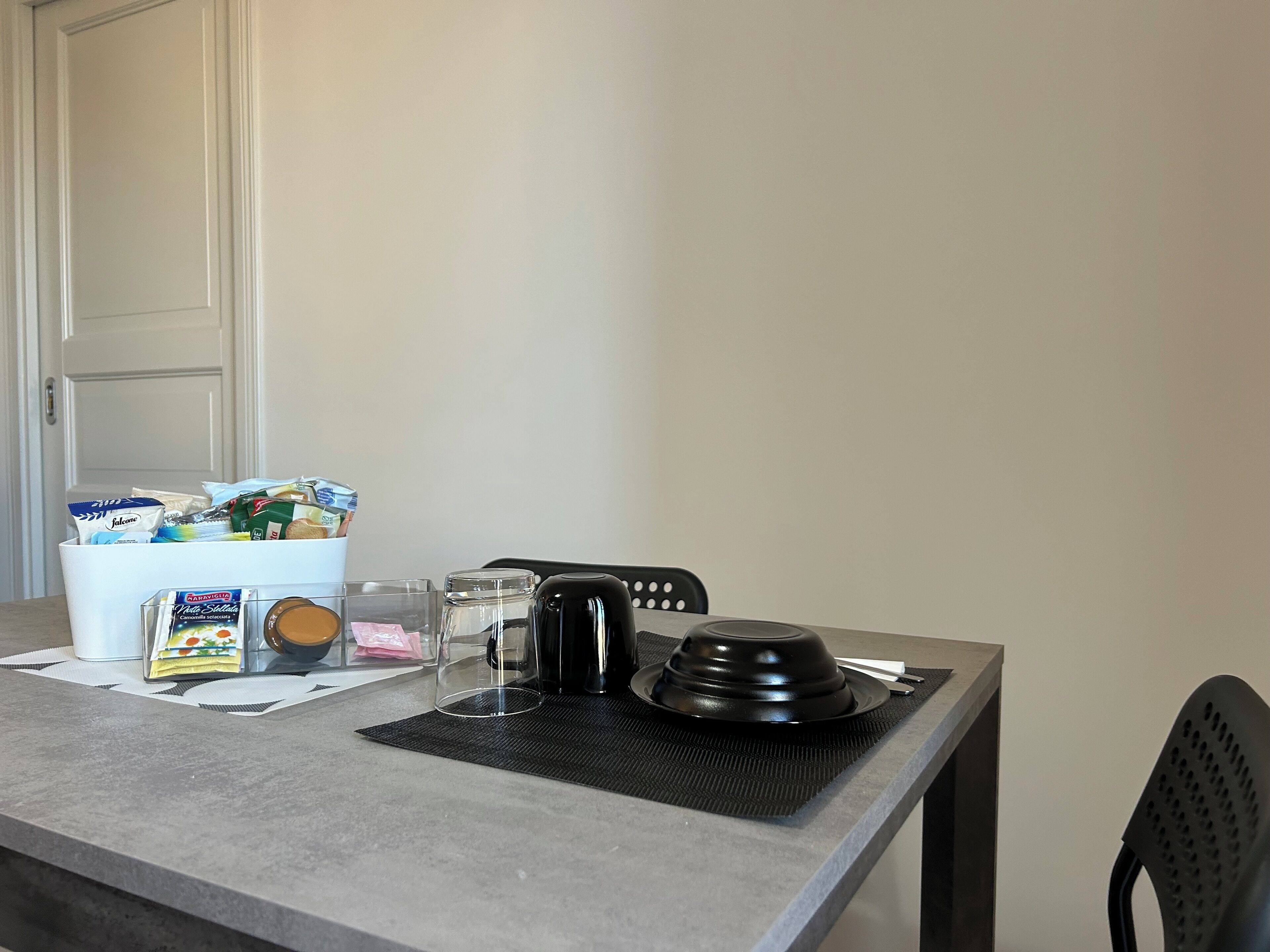 A kitchen counter with a coffee maker, a kettle, and a bowl of cereal.