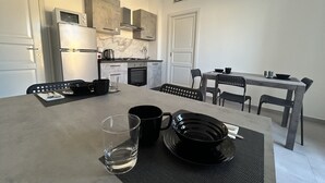 Eine moderne Küche mit Essbereich, einschließlich eines Tisches, der mit schwarzen Tellern, Tassen und einem Glas gedeckt ist.