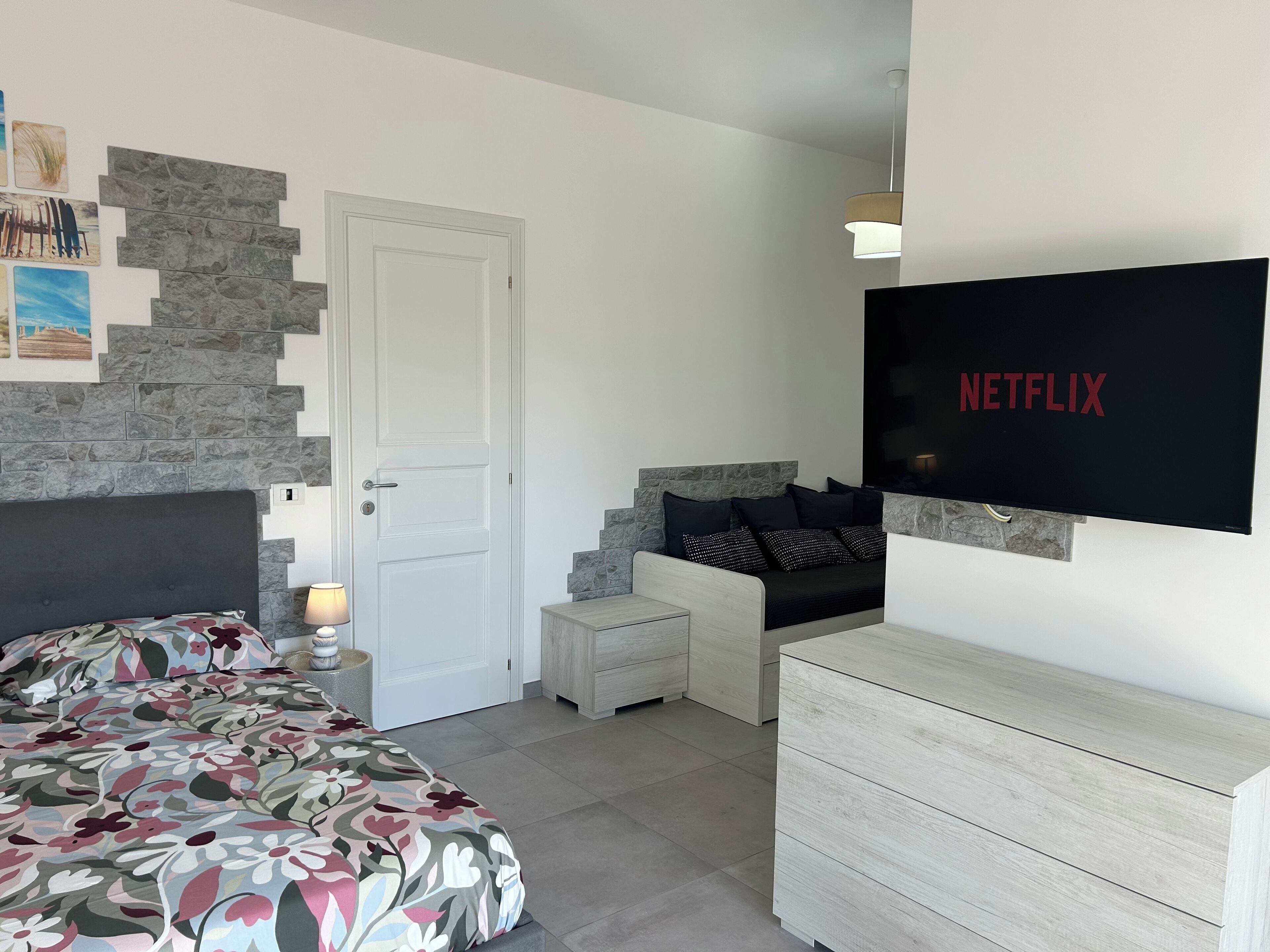 Un dormitorio moderno con cama, sofá, televisor y cómoda.