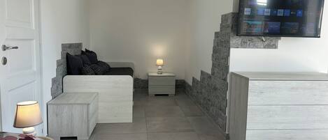 A bedroom with a bed, bedside table, lamp, and a TV mounted on the wall.