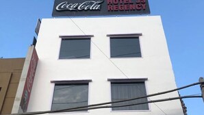Un immeuble orné d’une enseigne Coca-Cola et d’une enseigne pour l’hôtel JS Regency.
