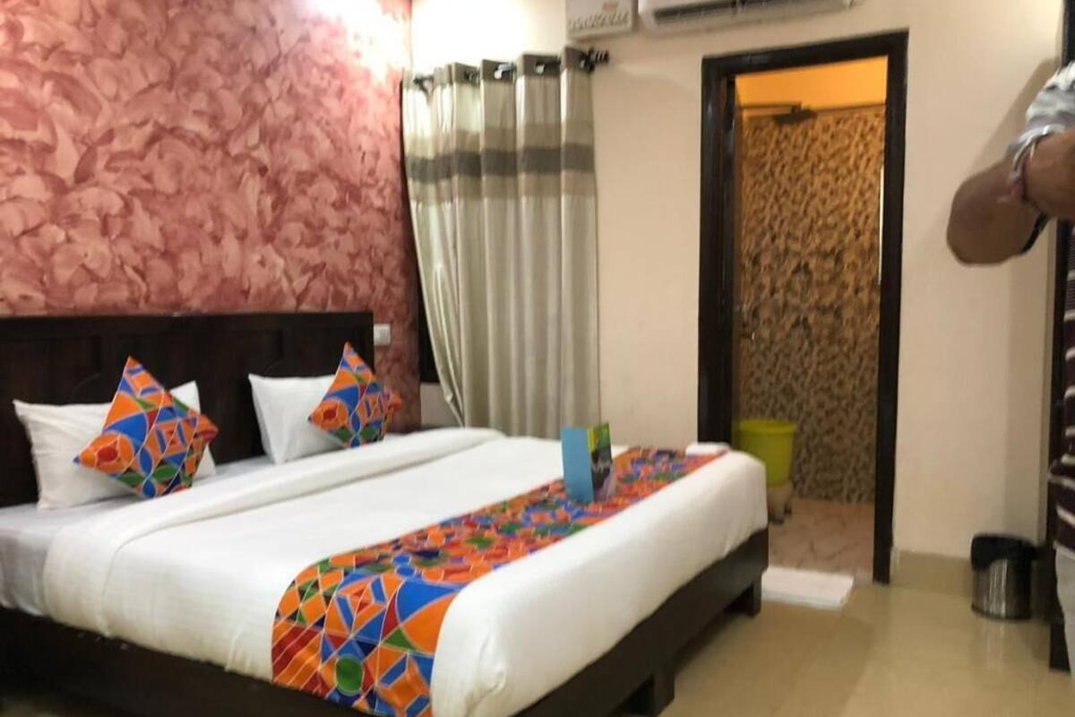 Ein Hotelzimmer mit Bett, Kopfteil, Vorhang und Tür.