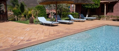 Une piscine à l’eau d’un bleu cristallin, entourée de chaises longues et de parasols.