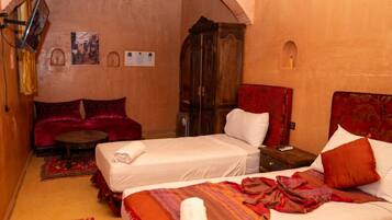 A hotel room with two beds, a sofa, a wooden cabinet, and a small table.