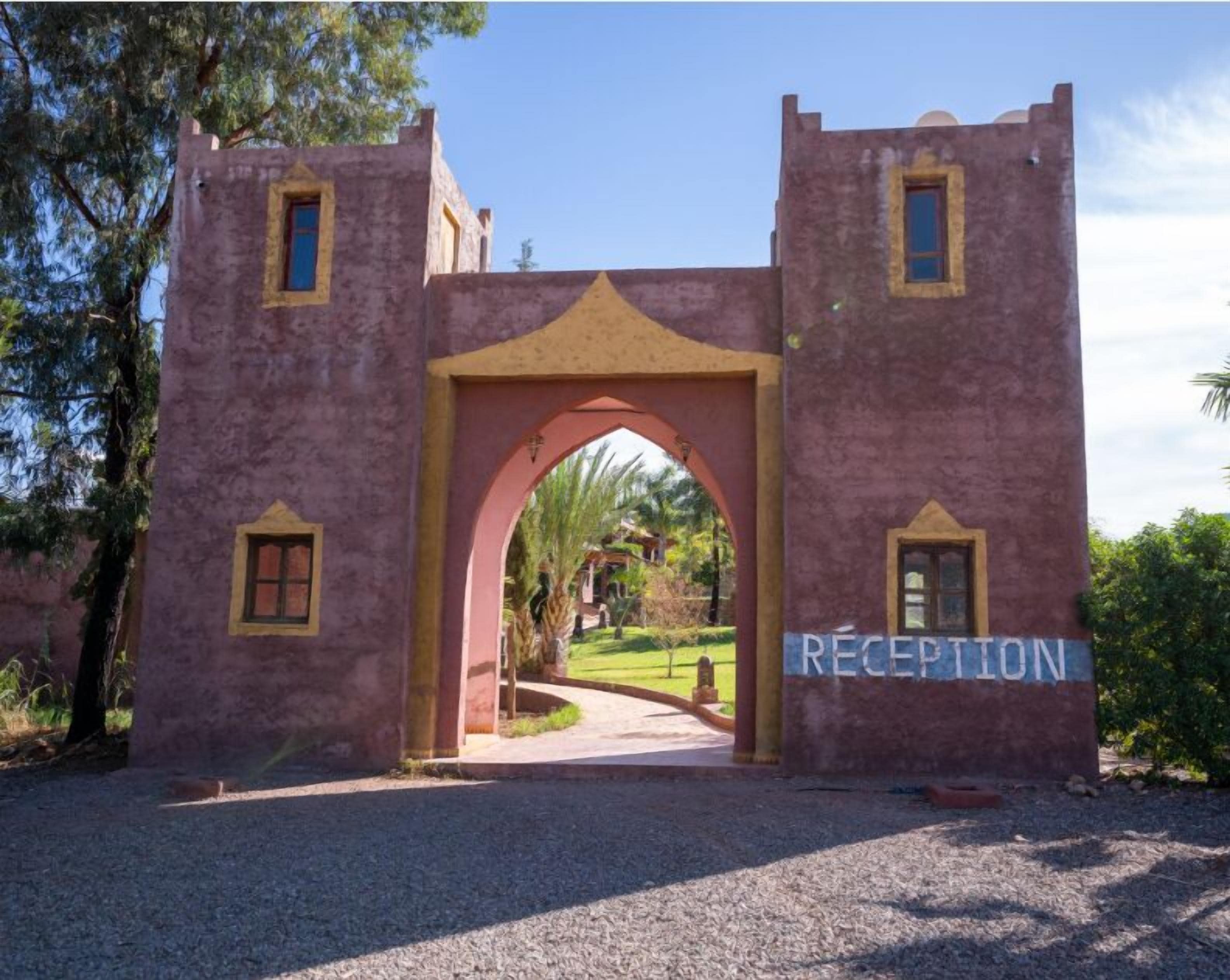 Un área de recepción con un gran arco, un letrero que dice "RECEPTION" y un camino que conduce a un jardín ajardinado.