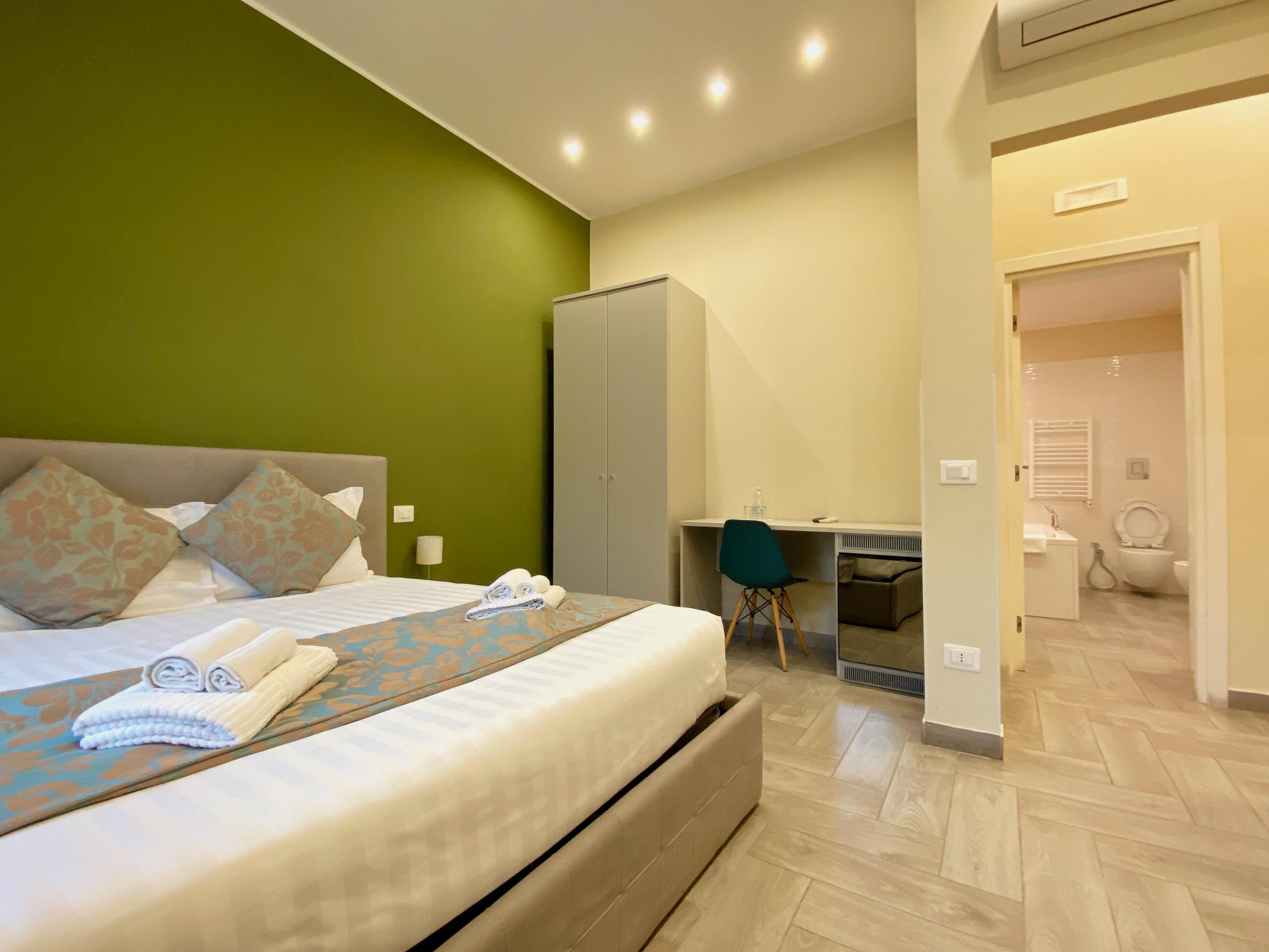 A hotel room with a bed, a desk, and a wardrobe.