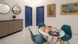 Un comedor con una mesa redonda, sillas color turquesa y un bufé con diferentes opciones de comida.