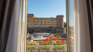 Vista de un castillo histórico a través de una ventana con cortinas.