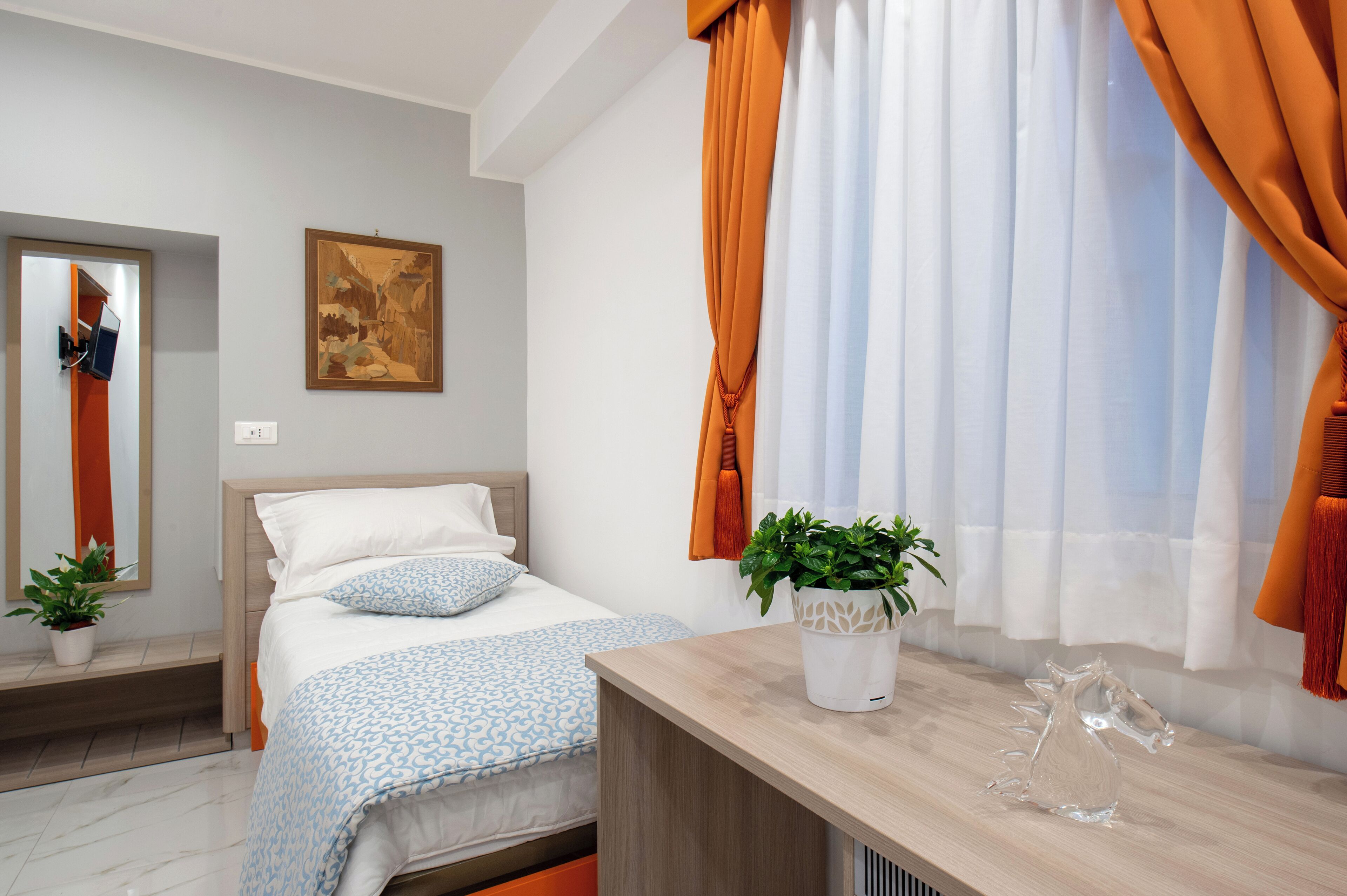 Un dormitorio moderno con cama, mesita de noche, espejo y ventana con cortinas.
