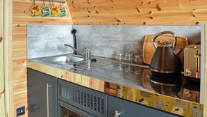 A kitchen with wooden walls, a stainless steel sink, a kettle, and a toaster.