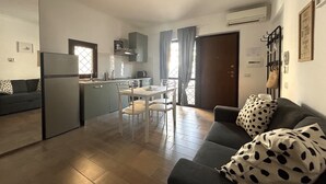 A compact living space with a kitchenette, dining area, and a sofa with a polka dot cushion. - Appartamento per Vacanze-Casa Sole (Fiumicino)