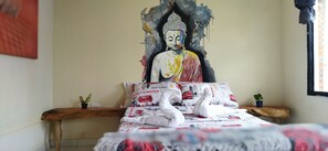 A bed with a patterned duvet, a wall painting of a Buddha, and a window with a view. - Terracota Mirador Filandia  (Filandia)