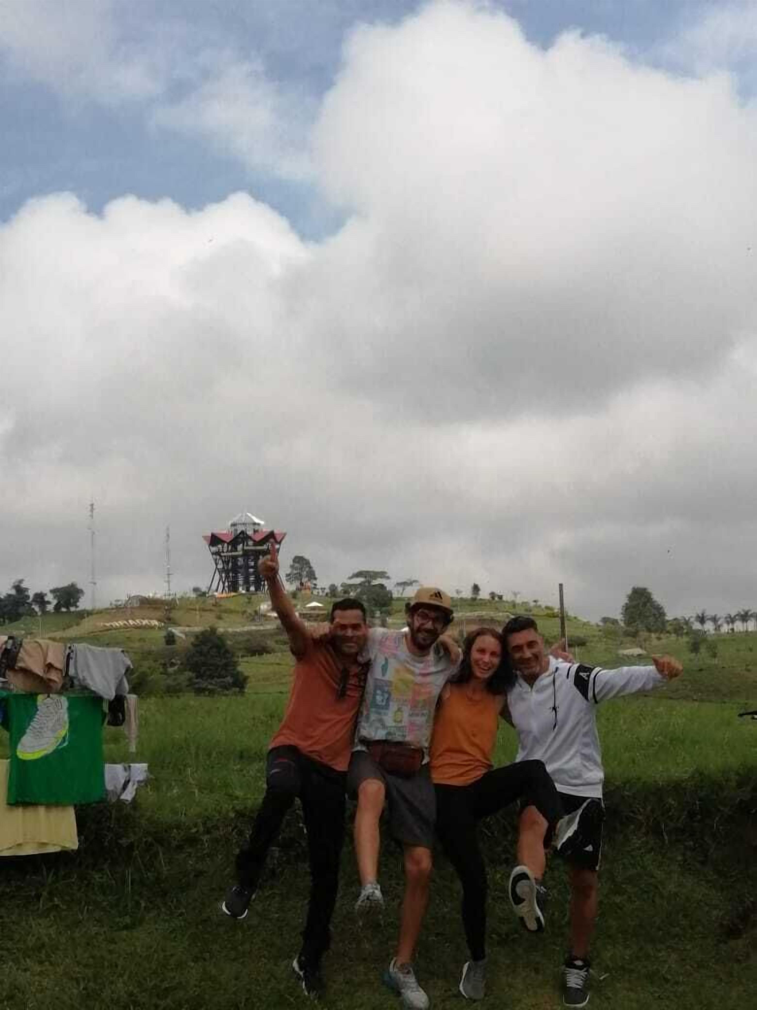 Een groep mensen die buiten op de foto gaat, met een groene constructie en een toren op de achtergrond.