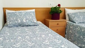Ein Doppelbett mit gemustertem Bettbezug, einem Holz-Kopfteil, einem Nachttisch mit Topfpflanze und passenden Kissen.