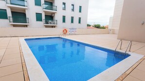 Ein Pool mit gefliestem Sonnendeck, einem Rettungsring und einem Schild mit Sicherheitsanweisungen.