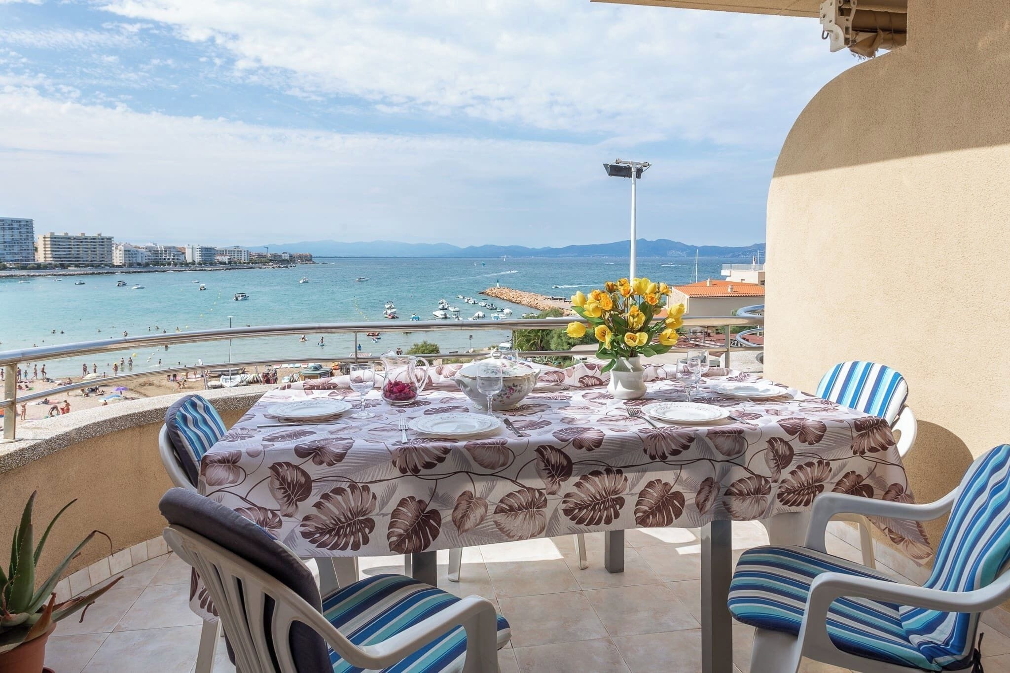 A table set for dining with a view of the sea and beach.