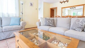 A living room with two sofas, a glass coffee table, and a wooden side table. - Casa Hermosa (L'Escala)