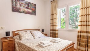 A bedroom with a bed, nightstands, a lamp, a painting, and curtains.