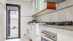 Una cuina moderna amb armaris blancs, fogó d'acer inoxidable i forn encastrat.