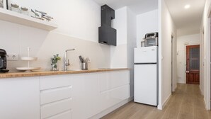 Une cuisine moderne avec des armoires blanches, un plan de travail en bois, un four encastré et une hotte noire.