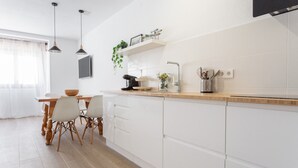 Une cuisine moderne avec des meubles blancs, un plan de travail en bois et un coin repas comprenant une table et des chaises.