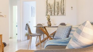 A modern living room with a sofa, a dining table with chairs, a vase with flowers, and a painting on the wall. - Bohemia Apartment with Terrace (L'Escala)
