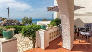 A patio with a view of the sea, a table with chairs, and potted plants. - Bohemia Apartment with Terrace (L'Escala)