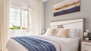 A bedroom with a bed, bedside tables, a window with curtains, and a painting on the wall. - Bohemia Apartment with Terrace (L'Escala)