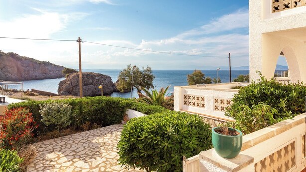 A coastal view with a stone pathway, greenery, and a building with a white facade and decorative window. - Bohemia Apartment with Terrace (L'Escala)